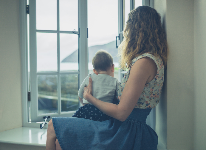 Single mom and baby looking out a window.